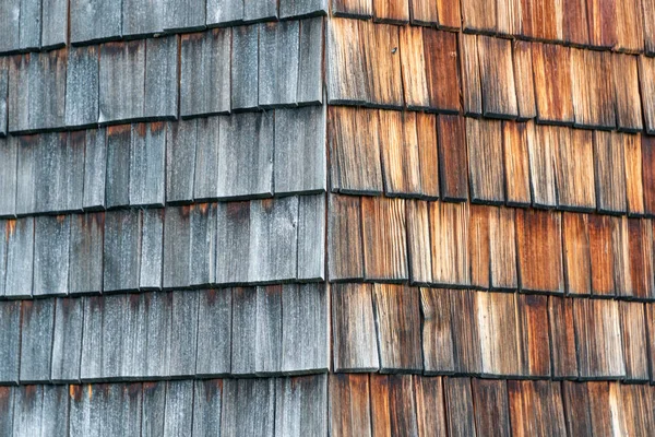 Verweerd en verschoten van de zon houten gordelroos die de gevel van een alpine huis. Houten textuur in grijs en oranje tinten. — Stockfoto