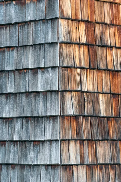 Verweerd en verschoten van de zon houten gordelroos die de gevel van een alpine huis. Houten textuur in grijs en oranje tinten. — Stockfoto
