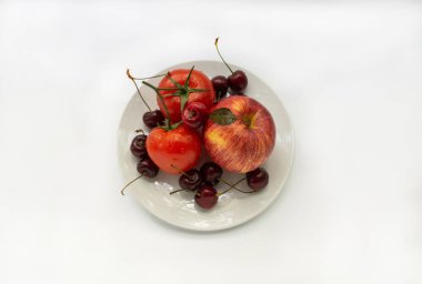 beyaz bir tabakta kırmızı sebze ve meyve