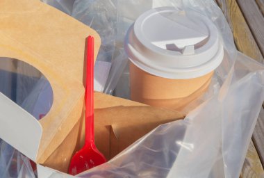 Yemekten sonra uygun olmayan atık imhası. Kahve için kağıt bardaklar, yiyecek için ambalajlar, plastik kapaklar plastik bir torbada toplanır.
