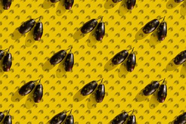 Çifte maruziyet. Katı gölgeli iki patlıcandan oluşan tekrarlanan bir patlıcan deseni sarı arka planda..