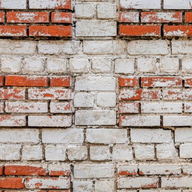 Beyaz ve kırmızı tuğlalardan yapılmış eski bir duvar parçası. Kırmızı tuğlalarda kabuğu soyulmuş beyaz boya var.