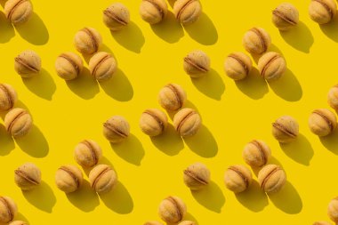 Sarı arka planda tekrarlanan cevizli kurabiye kalıbı. Kusursuz doku.