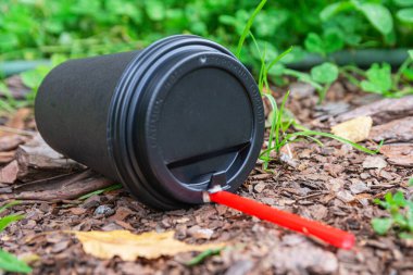 Parkta yerde boş siyah bir kahve fincanı yatıyor. Ev atıklarıyla çevre kirliliği.