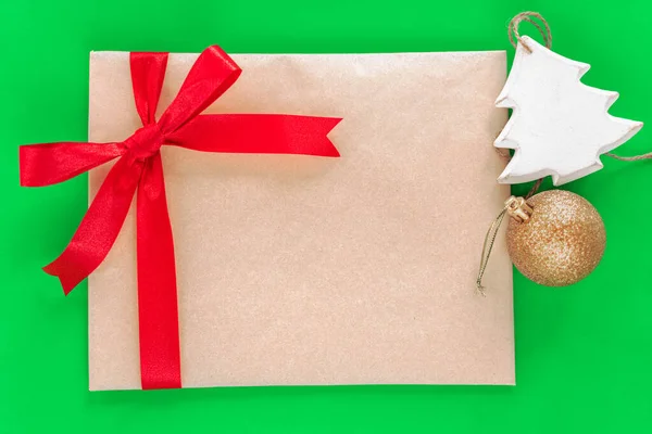 Kırmızı kurdeleli, Noel süslemeli, kraft kağıdından yapılmış bir zarfın şenlikli kompozisyonu. Noel ve Yeni Yıl konsepti. Düz yatıyordu.