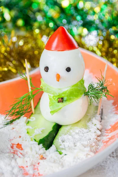 Kardan adam şeklinde süslenmiş haşlanmış yumurta, domates ve salatalık ziyafeti. Noel ve Yeni Yıl kavramı.