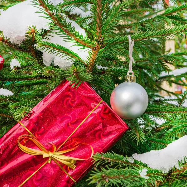 Regalo en un paquete rojo, una rama de un árbol de Navidad y una decoración de árbol de Navidad. Símbolos tradicionales de Año Nuevo y Navidad — Foto de Stock