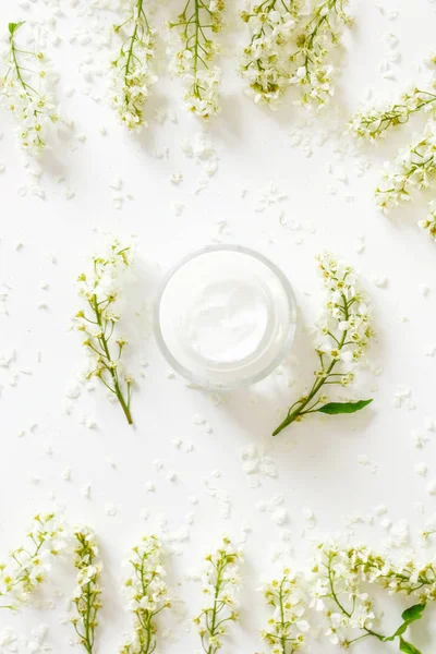 White Face Cream. Dermatology cosmetic hygienic cream with white flowers skincare product. Moisturizing face cream for spa treatment. Beauty background with facial cosmetic product. flat lay.