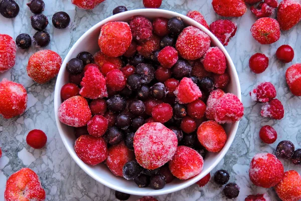 Frutti di bosco congelati.Vista dall'alto. Bacche deliziose congelate su sfondo blu, primo piano. Sottofondo di bacche congelate assortite . — Foto Stock