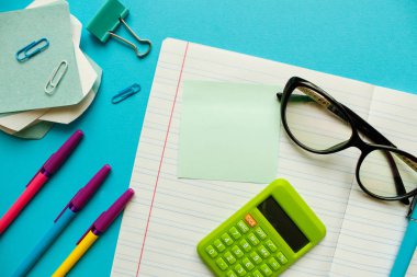 Çalışma alanı üst görünümü, kopyalama alanı. Kalem, defter ve diğer ofis malzemeleriyle dolu masa ofisi. Düz konum, üst görünüm ofis masası. Çalışma alanı çok az. Ofis masasının üzerinde. İş masası mavi üzerine..