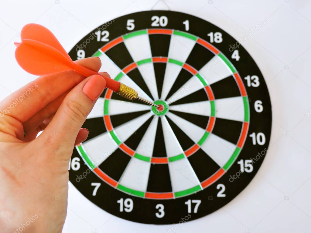 Dart arrow hitting in the target center of dartboard. Success hitting target aim goal achievement concept background.Darts and dart board.Close up shot of the dart arrow.Marketing concept. Dartboard.