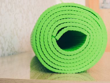 Yoga yapan bir kadın, yoga için gerekli ekipmanı üst perdeden izledikten sonra minderini yuvarlıyor. Yoga minderini beyaza sardım. Kopyalama. Beyaz arka planda siyah yoga minderi izole edilmiş..