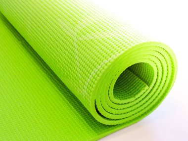 Egzersiz sonrası yoga minderini yuvarlayan bir kadın. Güzel bir bakış açısı. Sağlıklı yaşam, formda konseptler. Üstteki yeşil yoga paspas sporu izole edildi. Yoga minderini sarıp beyaza sarmaladık. Kopyalama alanı.