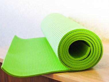 Egzersiz sonrası yoga minderini yuvarlayan bir kadın. Güzel bir bakış açısı. Sağlıklı yaşam, formda konseptler. Üstteki yeşil yoga paspas sporu izole edildi. Yoga minderini sarıp beyaza sarmaladık. Kopyalama alanı. 