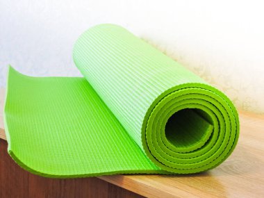 Egzersiz sonrası yoga minderini yuvarlayan bir kadın. Güzel bir bakış açısı. Sağlıklı yaşam, formda konseptler. Üstteki yeşil yoga paspas sporu izole edildi. Yoga minderini sarıp beyaza sarmaladık. Kopyalama alanı. 