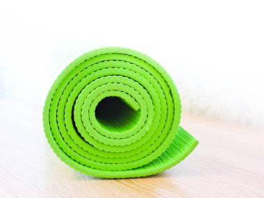 Egzersiz sonrası yoga minderini yuvarlayan bir kadın. Güzel bir bakış açısı. Sağlıklı yaşam, formda konseptler. Üstteki yeşil yoga paspas sporu izole edildi. Yoga minderini sarıp beyaza sarmaladık. Kopyalama alanı. 