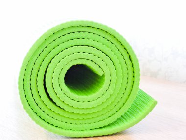 Egzersiz sonrası yoga minderini yuvarlayan bir kadın. Güzel bir bakış açısı. Sağlıklı yaşam, formda konseptler. Üstteki yeşil yoga paspas sporu izole edildi. Yoga minderini sarıp beyaza sarmaladık. Kopyalama alanı. 