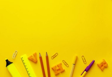 Metin alanı ile okul konseptine geri dönün. Üst görünüm. Boşluk Kopyala. Okul ofisi malzemeleri. Renkli Kırtasiye ile yaratıcı masa. Renkli kağıt klip. Sarı arka planda okul malzemeleri. Ofis Masası.