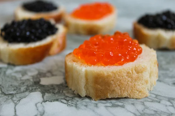 Top view of Sandwiches with red and black caviar on White marble background. Free space for text. Черная икра. Роскошный деликатес. Икра крупным планом. Морепродукты. Красная икра крупный план . — стоковое фото