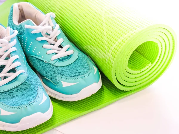 Woman rolling her Yoga mat after a workout - top view.Healthy life, keep fit concepts.Equipment for yoga. Top view green  yoga mat sport isolated.Rolled up yoga mat isolated on white. Copyspace.