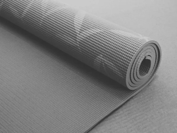 Woman rolling her Yoga mat after a workout - top view.Equipment for yoga. Rolled up yoga mat isolated on white. Copyspace. Black yoga mat isolated on white back background. — Stock Photo, Image