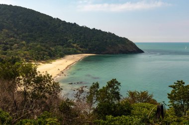 Koh Lanta, Tayland adasında yemyeşil ormanlarla çevrili uzak bir plaj manzarası, plaj tamamen boş ve pırıl pırıl Andaman Denizi ile pastoral görünüyor