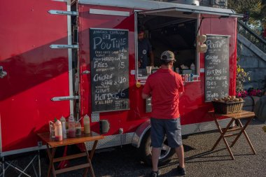 Victoria, Vancouver Adası, British Columbia, Kanada, 8 Temmuz 2019: Ünlü Kanada yemek poutine re food tezgahından sipariş kırmızı gömlekli bir adam