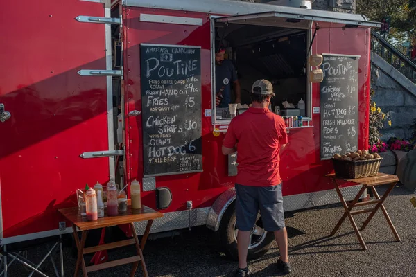 Victoria, Vancouver Island, British Columbia, Canada, juli, 8, 2019: een man in een rood shirt bestellen van een re Food Stall de beroemde Canadese gerecht poutine — Stockfoto