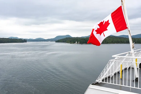 Eine Nahaufnahme der kanadischen Flagge, die im Wind auf der Rückseite der Fähre weht, während das Boot durch die Innenpassage fährt, britische Columbia, Kanada — Stockfoto