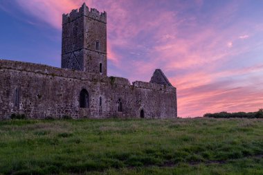 Clare Abbey harabeleri, şehir Clare, Irlanda 'nın hemen dışında bir Augustinian Manastırı bir görünüm arka planda güzel bir gün batımı ile