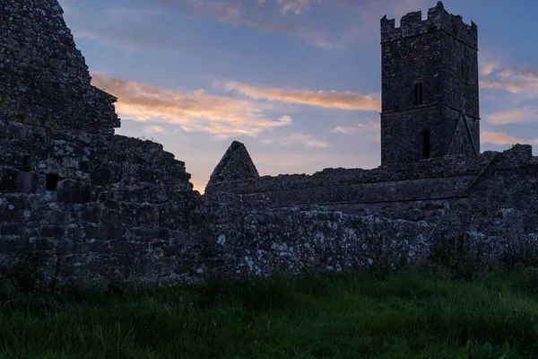Uma vista silhueta das ruínas da Abadia de Clare um mosteiro agostiniano nos arredores de Ennis, Condado de Clare, Irlanda ao pôr do sol — Fotografia de Stock