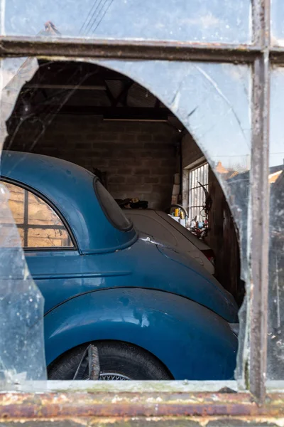 Une vieille voiture Morris Minor par la fenêtre cassée d'un garage — Photo