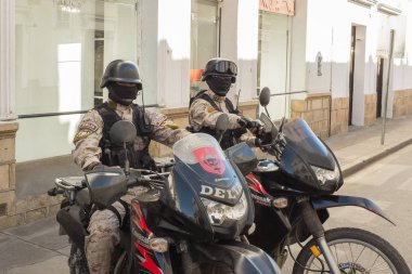 Özel Delta polis kuvvetlerinin iki üyesi Sucre Bolivya 'nın bir yan sokağında yüksek motorsikletleriyle oturuyorlar.