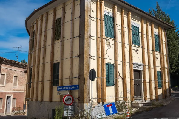 Un gran bloque de apartamentos en un pueblo italiano que ha sido dañado por un terremoto y está envuelto por cables de acero para evitar más daños —  Fotos de Stock