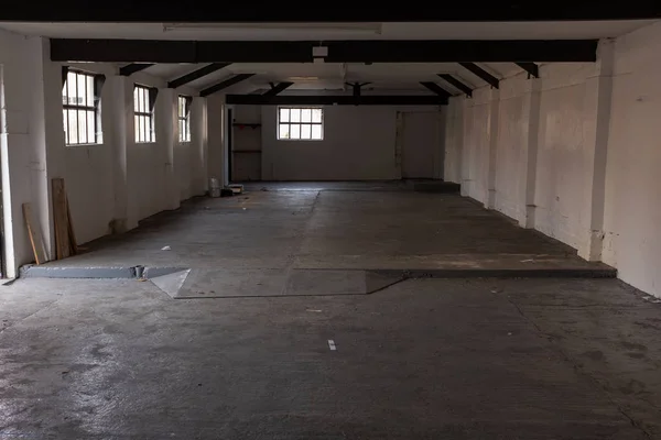 O interior de um edifício agrícola vazio com paredes brancas e vigas pretas — Fotografia de Stock