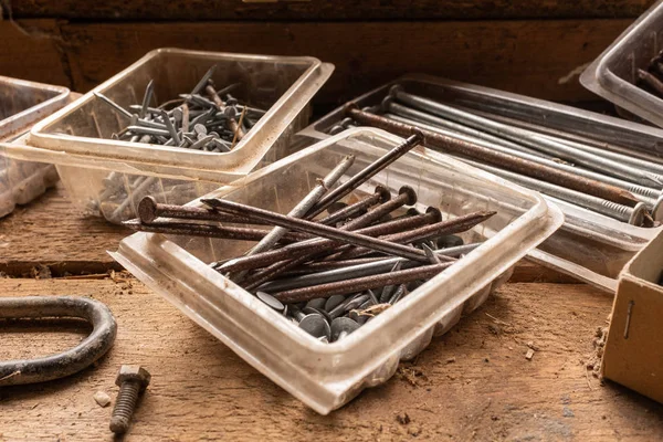 Een close-up van een assortiment spijkers en schroeven op een houten werkbank, natuurlijk licht — Stockfoto