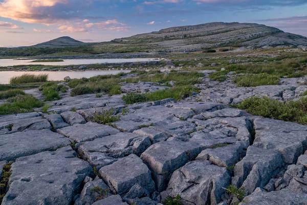 Střela do západu slunce na oslí a Marsu jako krajina, která je národním parkem Burren, County Clare, Irsko s malým jezerem v popředí — Stock fotografie