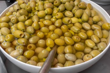 Bir çiftçi pazarında Satılık salamura lezzetli görünümlü yeşil zeytin dolu bir gümüş kase yakın.