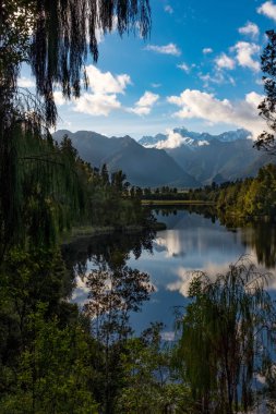 İnanılmaz güzel Matheson Gölü yaprakları ile çerçeveli bir portre görünümü, Çarpıcı Güney Alpleri ve durgun sularda görkemli Mt Cook yansıması ile Yeni Zelanda.