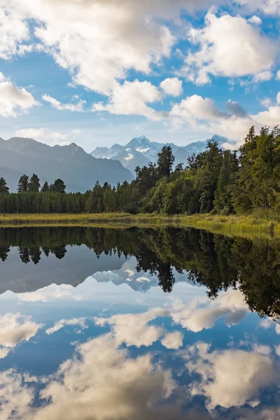 A portrait view of the incredibly beautiful Lake Matheson, New Zealand with the reflection of the stunning Southern Alps and the majestic Mt Cook in the still waters.