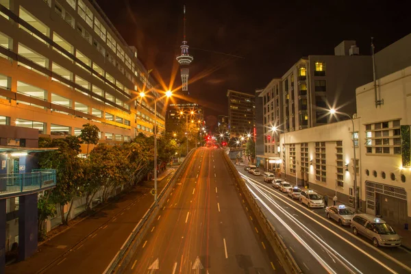 Auckland, neuseeland, 26. November 2014; Autoleuchten, die nachts bei langer Belichtung aufgenommen werden, erzeugen lange Wege und einen verschwommenen Effekt gegen die nächtliche Skyline — Stockfoto