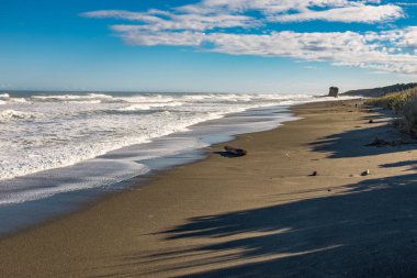 Güneşli bir günün sonunda boş bir plaj, düşmeye başlayan uzun gölgeler, güzel mavi gökyüzü