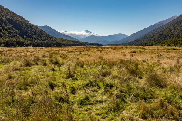 ハースト峠を渡り 澄んだ青空に対して ニュージーランドのオタゴの南アルプス山脈に向かって平坦な谷を見下ろす — ストック写真