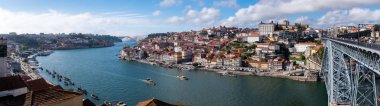 Douro Nehri 'nin panoramik manzarası Porto şehrinin önünde Ponte Luiz köprüsü ve nehre bağlı geleneksel botlarla sinsice ilerliyor. 