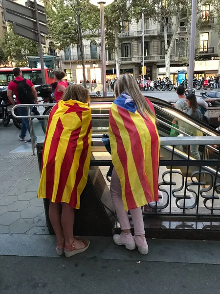 Two females wrapped in Catalonia Flag at the top of an escalator as they wait for friends to join them for a protest for the right to vote — ストック写真