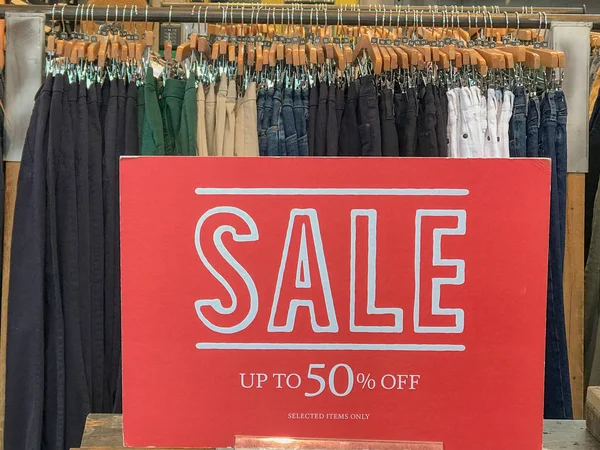 Un letrero rojo de la venta dentro de una tienda de ropa publicidad 50% off — Foto de Stock