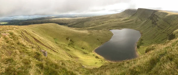 A panorámás kilátás nyílik a gördülő zöld dombok és hegyek a Brecon Beacons Wales egy tó az előtérben — Stock Fotó