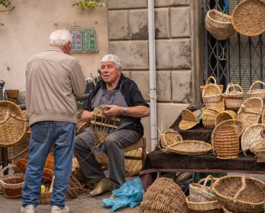 İtalya 'nın tepedeki bir kasabasında el işi pazarında sepet dokumacı bir erkek.