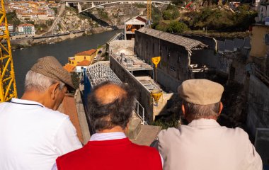 Üç yaşlı beyefendinin arkasından Porto 'nun ortasındaki büyük bir şantiyeye bakıyorlar.