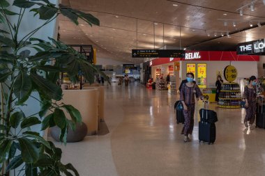 Auckland, Yeni Zelanda, 6 Ağustos 2020, Singapur Havayolları personeli boş bir Auckland uluslararası terminalinde maske takıyor..